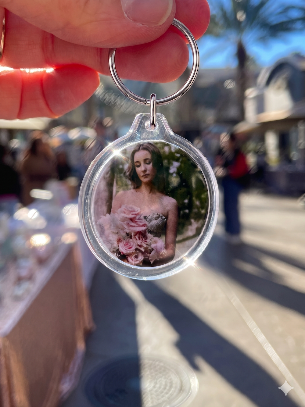 custom Keychain with a photo of a woman holding flowers, held by a hand outdoors.